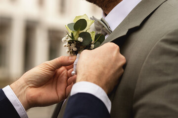 Vor der Trauung. Der Trauzeuge befestigt einen Blumenanstecker am Anzug des Bräutigams.
