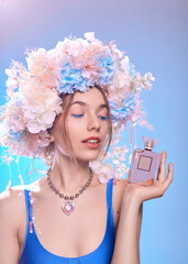 a woman in a flower wreath poses with a bottle of perfume in her hands