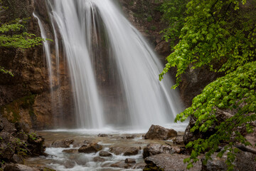 Fototapeta na wymiar Beautiful waterfall in the forest among green trees