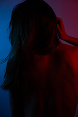 Intense young woman, blue and red lighting on back. Female body in different colors
