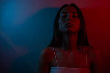 Portrait photo of a woman in blue and red colors. Concept of internal anxiety, stress and danger.