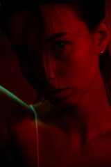 portrait photo of a woman in red neon light. Woman with a stern look directly at the camera
