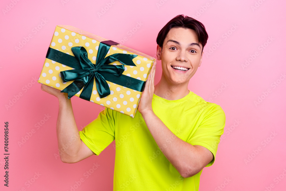 Sticker Photo portrait of nice teen man hold giftbox enjoy holiday shopping dressed stylish yellow clothes isolated on pink color background