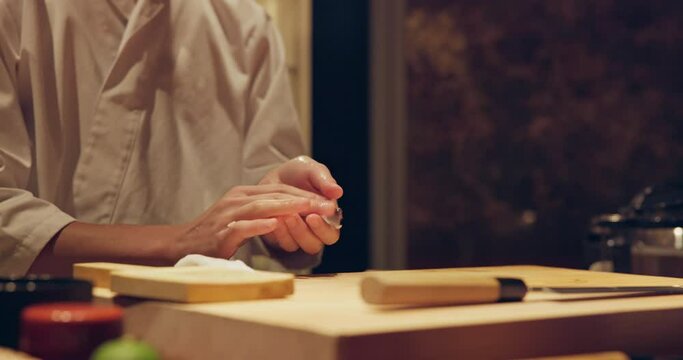 Sushi chef hands, fish and rice with meal preparation on table at diner, cuisine and cooking in night. Person, kitchen or restaurant with catering job, ready and service for nutrition, diet or snack