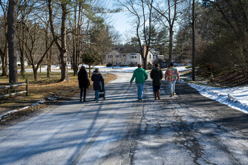 Photograph of a group of people walking on a road with a mother pushing a baby stroller