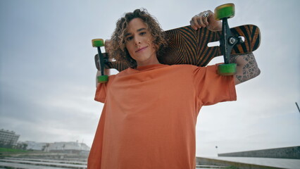 Portrait skater boy posing camera at summer playground. Guy holding skateboard © stockbusters