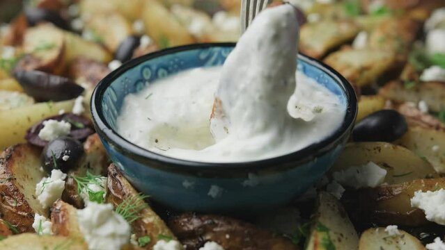 Dipping Greek fried potatoes in lemon yogurt sauce