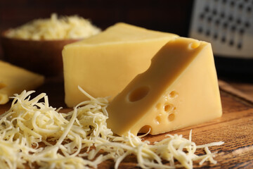 Grated and cut cheese on wooden board, closeup
