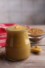 Tasty mustard sauce in jar on wooden table, closeup