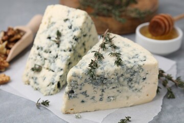 Tasty blue cheese with thyme on grey table, closeup