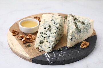 Tasty blue cheese with thyme, honey and walnuts on white marble table