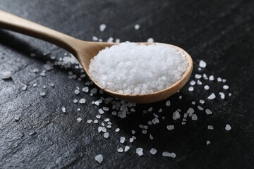 Fototapeta na wymiar Organic white salt and spoon on black table, closeup
