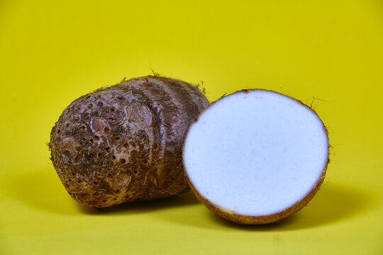 closeup of taro root vegetable, eddo malanga, yellow background