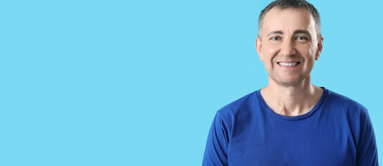 Portrait of handsome smiling mature man on light blue background with space for text