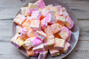 Colorful pink, orange and yellow homemade marshmallows made of egg whites and sugar on a plate