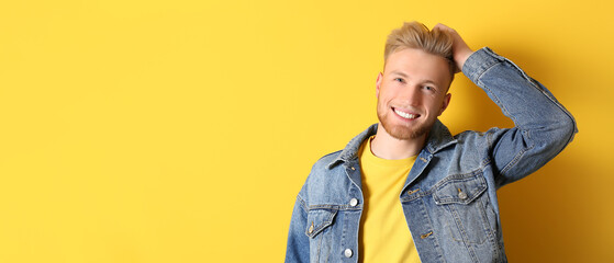 Portrait of handsome smiling young man on yellow background with space for text