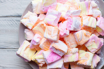 Colorful pink, orange and yellow homemade marshmallows made of egg whites and sugar on a plate