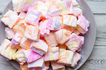Colorful pink, orange and yellow homemade marshmallows made of egg whites and sugar on a plate