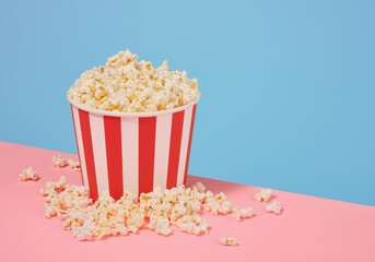 Big bucket of popcorn. Lots of popcorn scattered on the surface. Copy space for text.