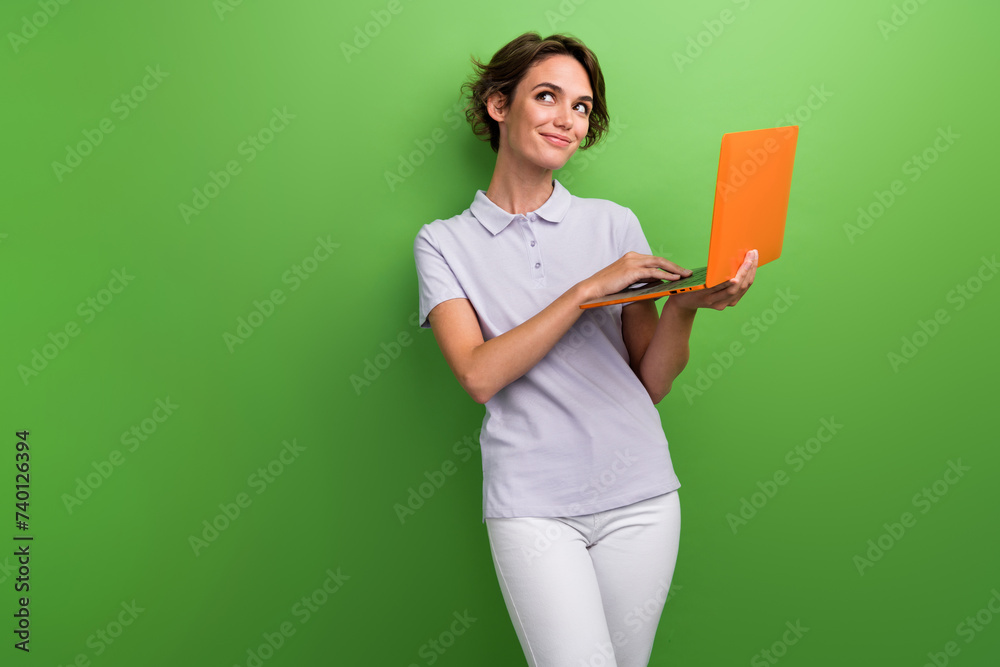 Sticker Photo of lovely girl wear trendy polo hold netbook recommend buy modern device look up empty space isolated on green color background