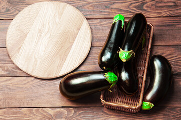 ripe eggplant on a wooden stand on a brown background. black aubergine on a light background	