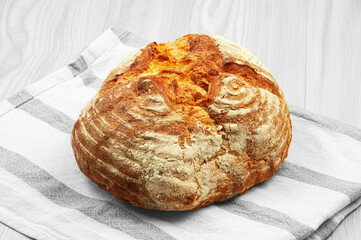 baked Italian bread on a light wooden table. ciabatta on a white towel on a wooden background
