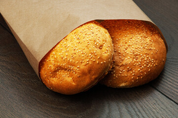 burger buns in a package on a wooden background. appetizing buns with sesame in a paper package	