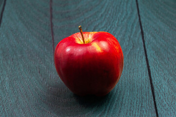 red ripe apple on a dark wooden background.
