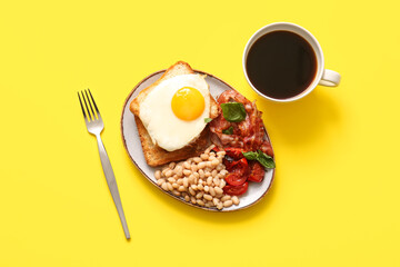 Plate with tasty English breakfast and cup of coffee on yellow background