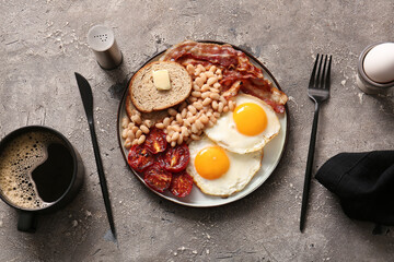 Plate of tasty English breakfast with fried eggs on grey background