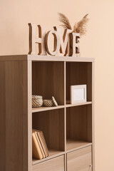 Wooden shelving unit with decor near beige wall
