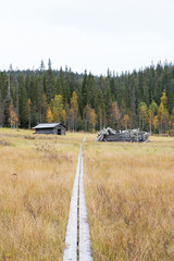 Old wooden hay barns next to Riisin rietas trail wooden path in autumnal Riisitunturi National Park, Northern Finland