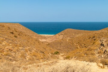 Sendero de descenso desde el acceso a la playa de Los Muertos, Carboneras, Almería, España. Vista cenital de la playa a orillas del mar Mediterráneo un soleado día de verano desde el aparcamiento.