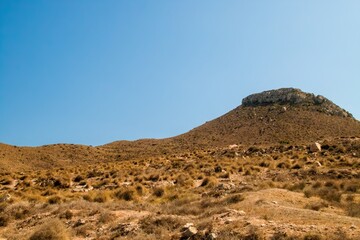 Fototapeta na wymiar Mesa de Roldán hill from Enmedio cove in Níjar, Almería, Spain. Hill located on the coast of the Mediterranean Sea, next to the district of Agua Amarga.