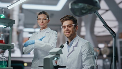 Smiling scientists looking camera in modern laboratory close up. Two researchers