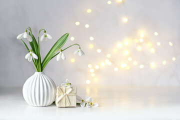 snowdrops flowers and gift box on table, abstract light background. white snowdrops, symbol of...