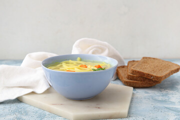 Bowl of tasty chicken soup on table against white background
