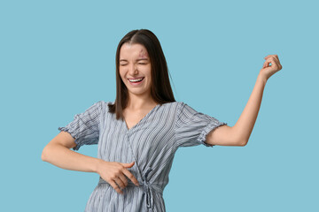 Pretty young woman playing imaginary guitar on blue background