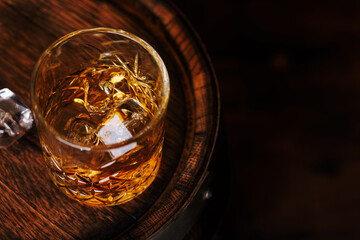 Whiskey glass with ice on a rustic barrel, a classic sip