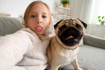 Little girl with cute pug dog taking selfie at home, closeup