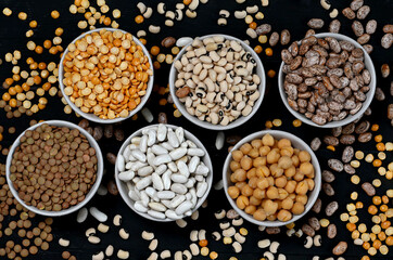 Scene with a variety of beans which are scattered around an array of bowls.