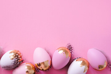 Easter eggs with golden glitter on pink background with copy space