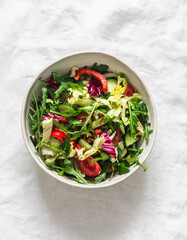 Fresh vegetable salad with a variety of vegetables and herbs on a light background, top view. Vegetarian diet food