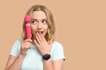 Thoughtful young woman with vibrator on beige background