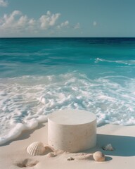 A solitary cylindrical pedestal stands on a sandy shore, accompanied by delicate seashells, as turquoise waves gently roll in the background.