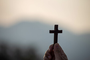 Human hand holding cross with light sunset background. christian concept - obrazy, fototapety, plakaty