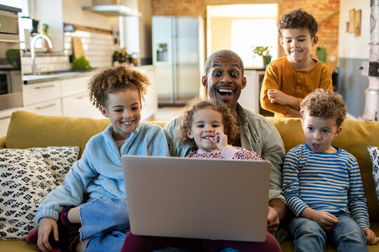 Happy father with children using laptop on the couch at home