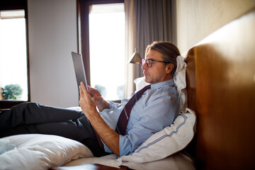 Mature businessman using a tablet while in a hotel room
