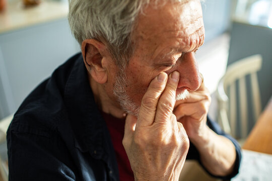Senior man contemplating with hand on face at home