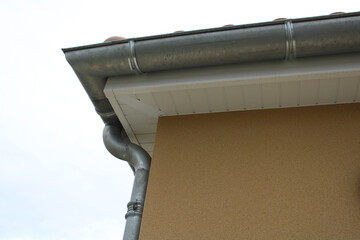 Gouttière zinc gris sur la façade de la maison, descentes et lambris de sous-face en PVC blanc